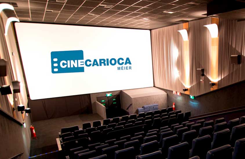 Sala de cinema moderna do CineCarioca Méier, com poltronas azuis, iluminação lateral e tela grande ao fundo.