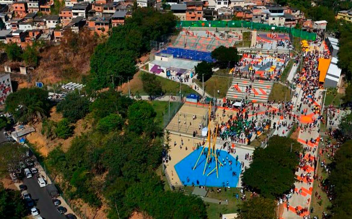 Vista aérea do Parque Pavuna, no Rio de Janeiro, mostrando quadras esportivas, áreas de lazer coloridas e grande público circulando.