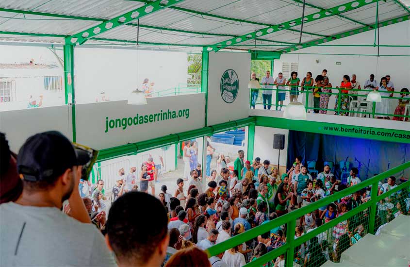 Público reunido na Casa do Jongo da Serrinha, em Madureira, Rio de Janeiro, durante uma roda de jongo, com pessoas assistindo no térreo e no mezanino do espaço cultural.