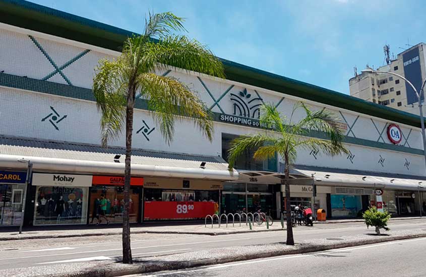 Fachada do Shopping do Méier, no Rio de Janeiro, com lojas no térreo, palmeiras na calçada e céu ensolarado.