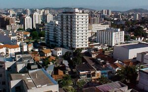 Vista aérea do Méier, no Rio de Janeiro, com prédios residenciais e comerciais ao centro e morros ao fundo em dia ensolarado.