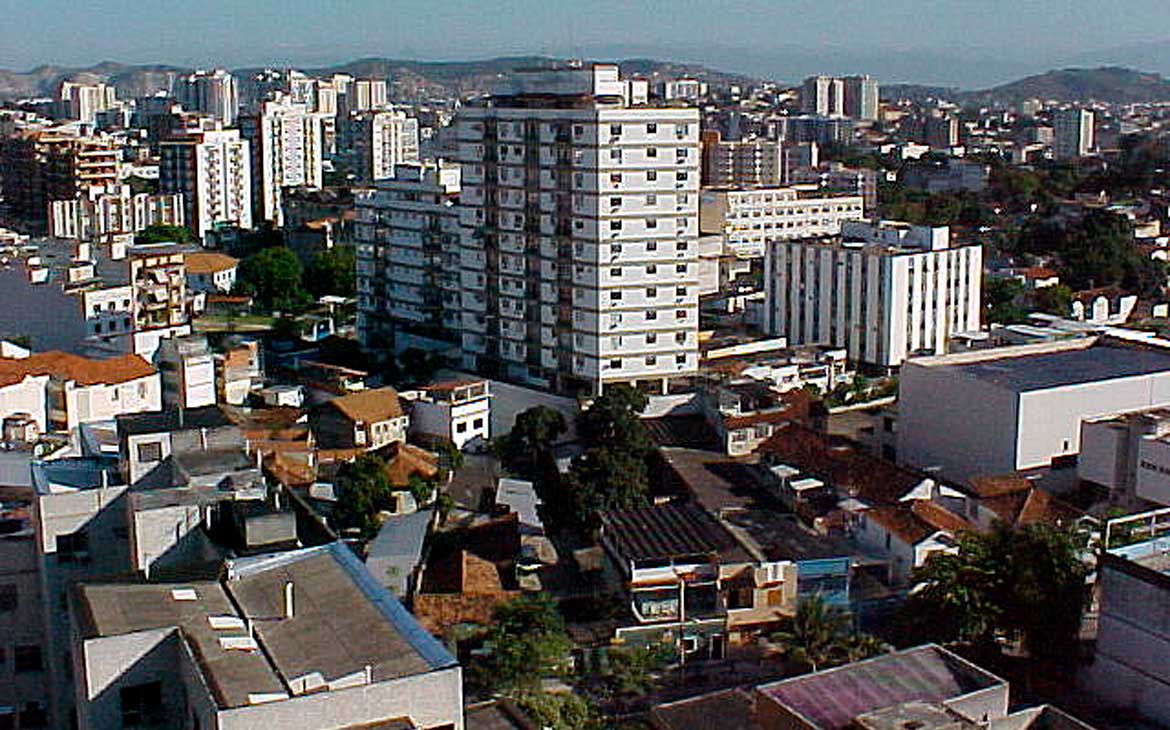 Vista aérea do Méier, no Rio de Janeiro, com prédios residenciais e comerciais ao centro e morros ao fundo em dia ensolarado.