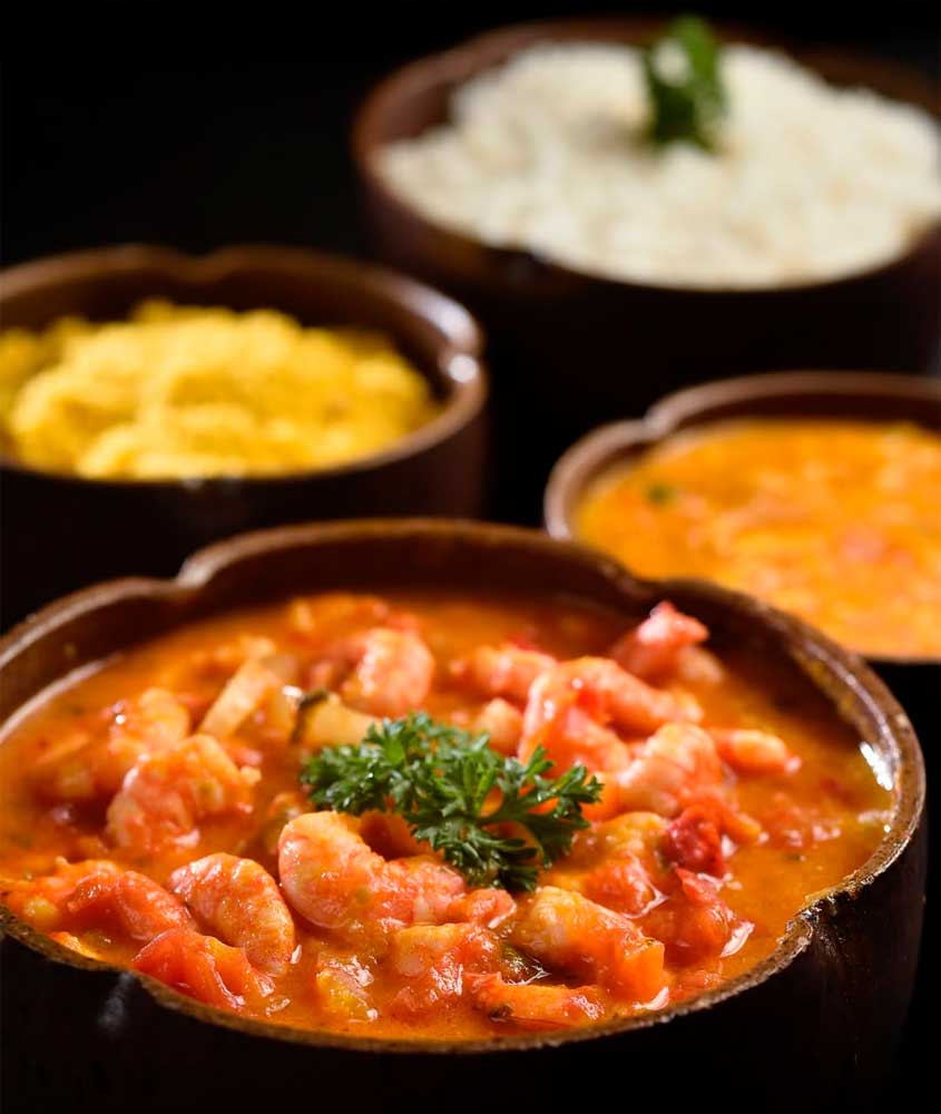 Bobó de camarão servido em panela de barro, acompanhado de arroz branco, farofa e pirão.